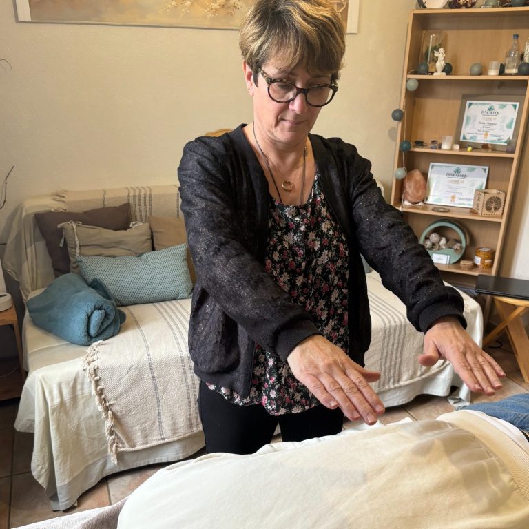 Femme en train de pratiquer un soin énergétique sur une table de massage.